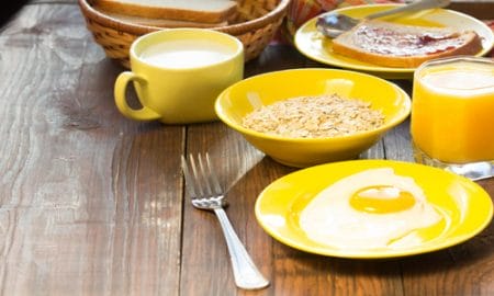 Breakfast served in yellow tableware - eggs, oatmeal, orange jui