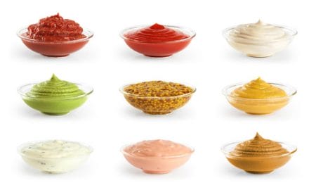 Bowls with sauces ketchup and mustard on white background.
